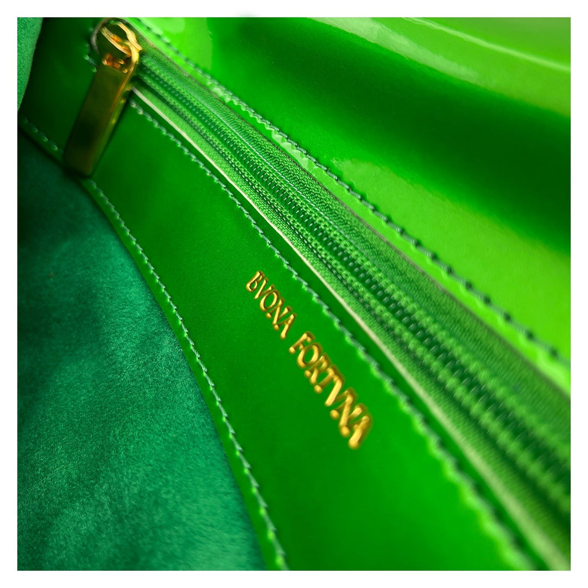 Close-up of the interior of Bvona Fortvna's green Italian leather handbag, featuring a matching green zip pocket with gold zipper pull and gold 'Bvona Fortvna' logo embossing